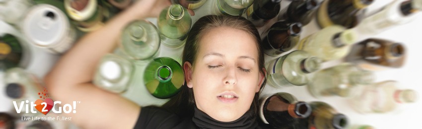 Young, partially drunk woman surrounded by bottles 