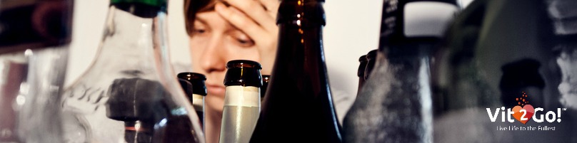 Young man surrounded by many bottles of alcohol